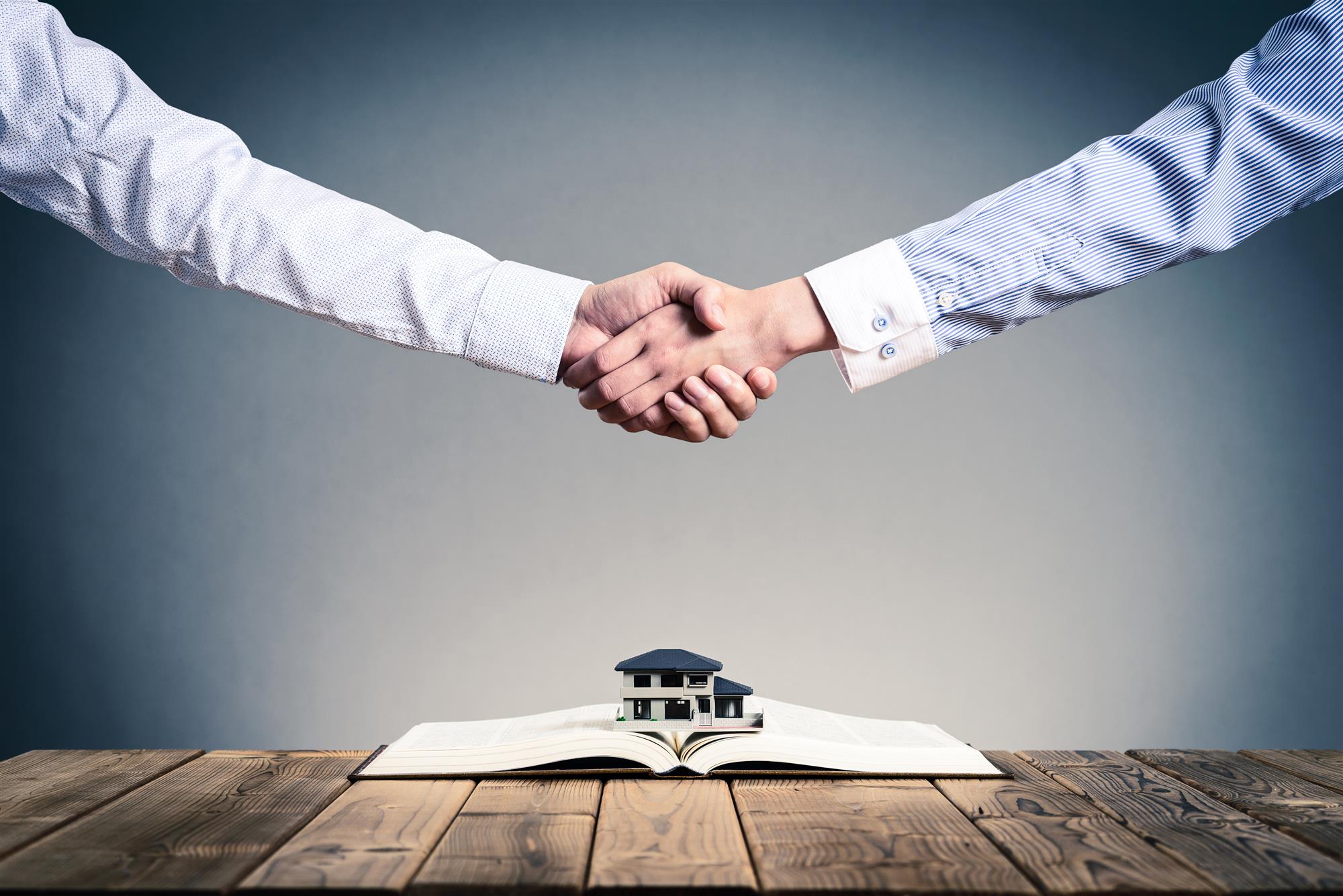 Professional handshake above a model home